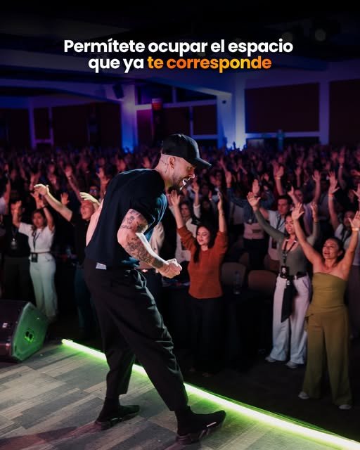Ponente con el público de pie y los brazos en alto en la Cumbre de los Millonarios Conscientes